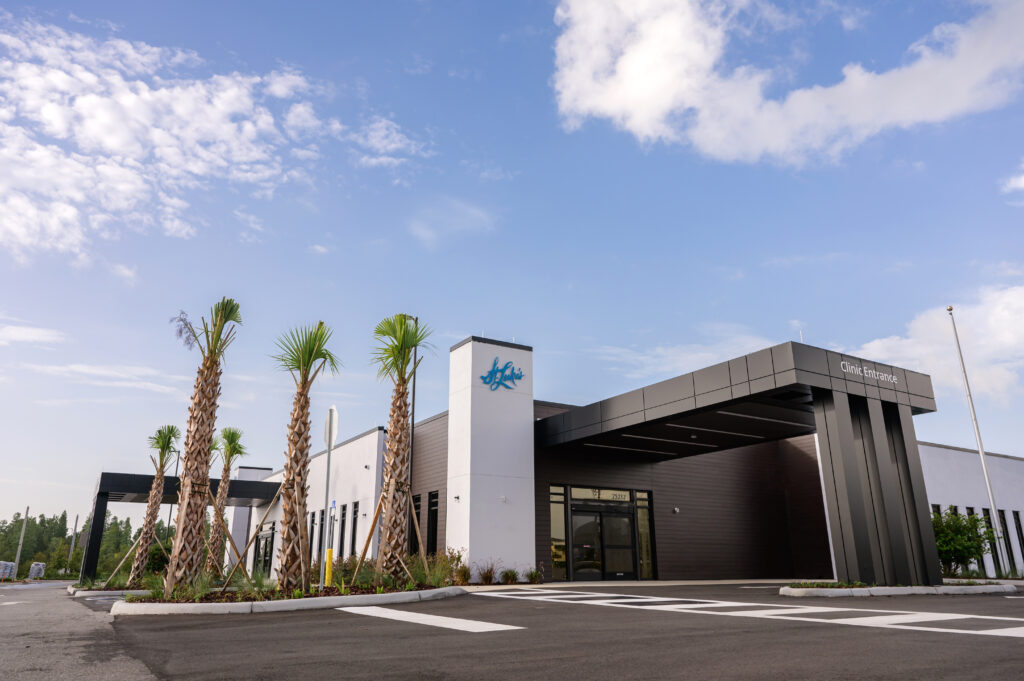 Exterior view of St. Luke’s Eye Clinic building under a clear blue sky, featuring modern white and dark gray architecture, palm trees, and a spacious parking lot